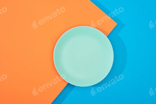 Preview: top view of empty plate on colorful blue and orange surface