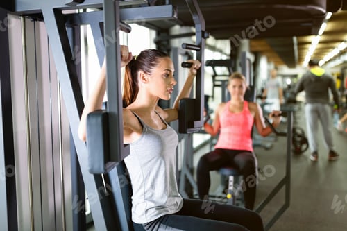 Preview: Young women exercising on machine in gym