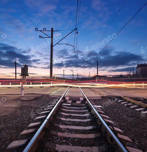 Preview: Rail crossing with blurred car lights at beautiful sunset. Railw