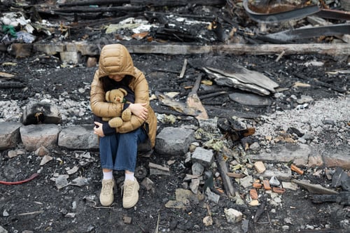 Preview: A girl next to a house destroyed by the war. War in Ukraine. Ukrainian refugees. Child in the ruins