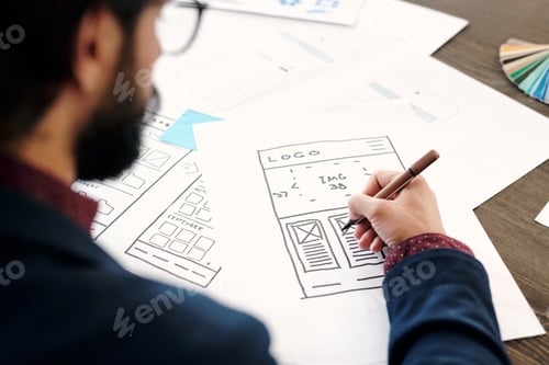 Preview: Hand of young male developer of mobile application holding pencil over sketch