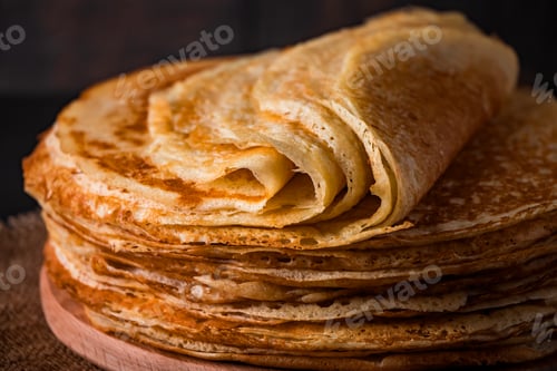 Preview: A stack of thin pancakes on a dark wooden background.