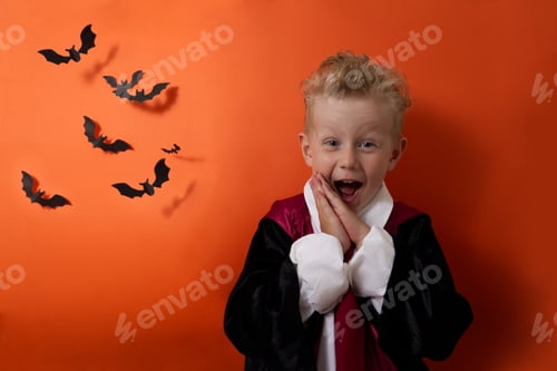 Preview: A boy in a vampire costume emotionally looks at the camera on an orange background