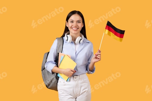 Preview: Female student with German flag holdign notebooks, smiling at camera