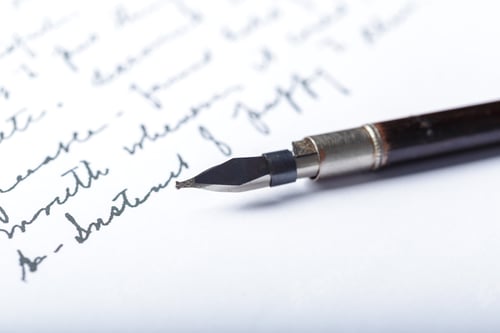 Preview: Close view of a fountain pen writing on paper with cursive letters in a simple setting