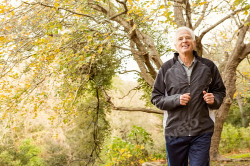 Preview: Senior man jogging park trail wearing dark running jacket, track pants, athletic shoes, copy space