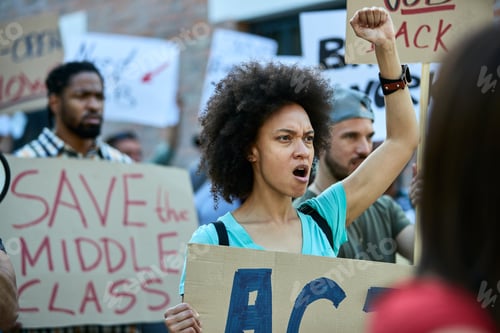 Preview: Young black woman with raised fist shouting on a protest for human rights.