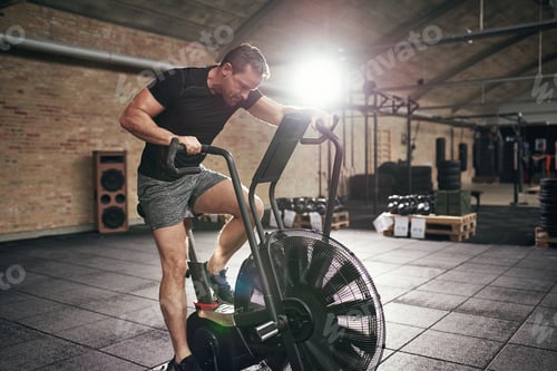 Preview: Muscular male working out on cycling machine