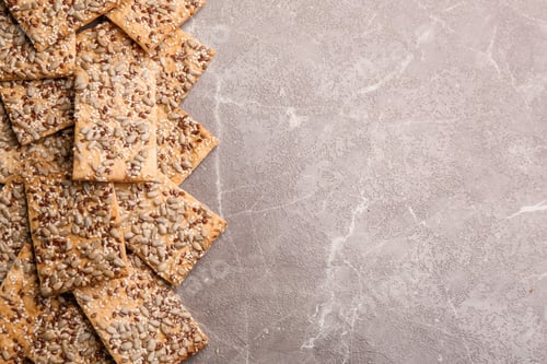 Preview: Many delicious crackers on grey table, flat lay. Space for text