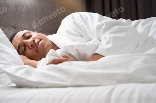 Preview: Cute multiracial man sleeps in bed on soft pillow