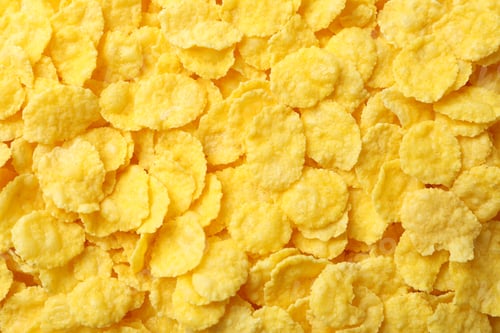 Preview: Dry uncooked corn flakes on whole background, close up