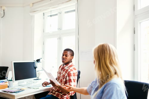 Preview: Coworker passing document to colleague in office
