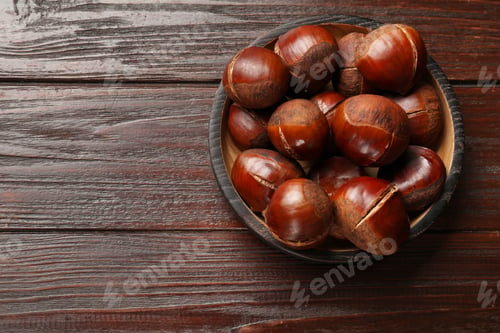 Preview: Roasted edible sweet chestnuts on wooden table, top view. Space for text