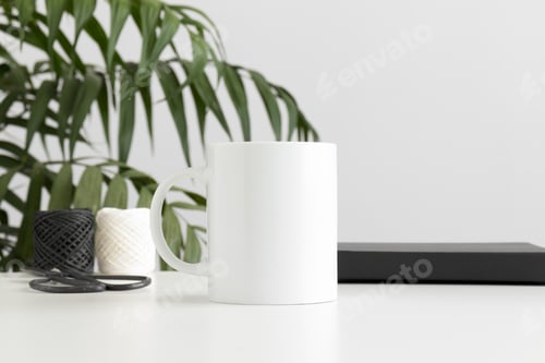 Preview: Mug mockup with workspace accessories on a white table and a palm plant.