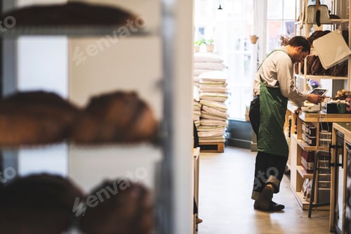 Preview: Artisan bakery making special sourdough bread, racks of bread and a baker in the background.