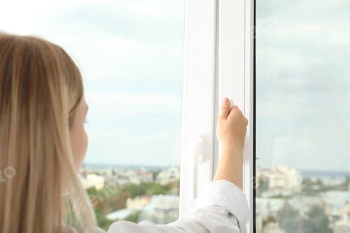 Preview: A woman's hand opens a window with a view of the city