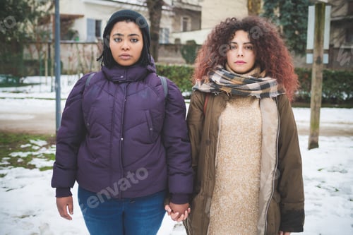 Preview: portrait of two multiracial women looking camera with serious gaze