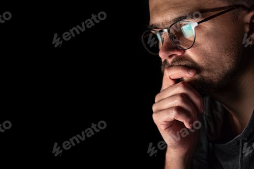 Preview: A man with glasses in the dark looks at the computer screen, copy space.