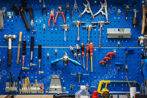 Preview: Large selection of hand tools organised and hung up neatly on a blue tool board on the wall of a
