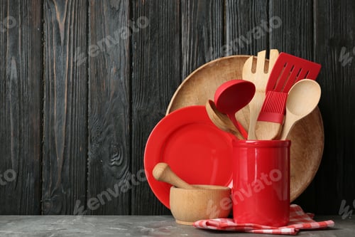Preview: Different kitchen utensils on grey table against dark wooden background. Space for text