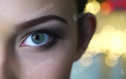 Preview: close-up on woman eye against bokeh light.