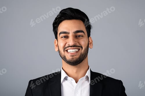 Preview: Confident Middle Eastern businessman smiling in a corporate studio setting