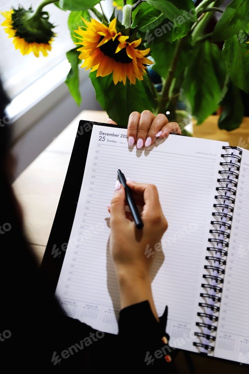 Woman Plans Calendar at Home with Sunflowers