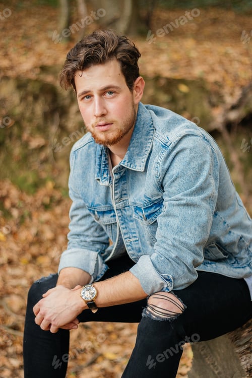 Preview: Vertical shot of a young handsome guy in an autumn park
