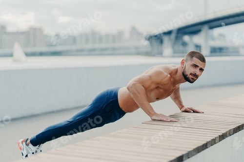 Preview: Sporty muscular man in sportswear does push up exercise has concentrated serious expression