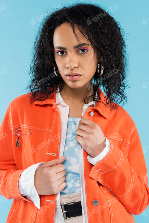 Preview: portrait of brunette african american woman in bright orange jacket looking at camera isolated on