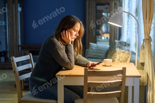 Preview: Sad Woman with Phone at Wooden Table Indoors