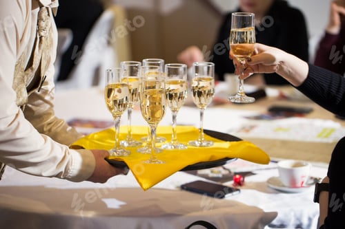 Preview: Waiter served champagne glasses on a tray in a fine dining restaurant and woman takes a glass