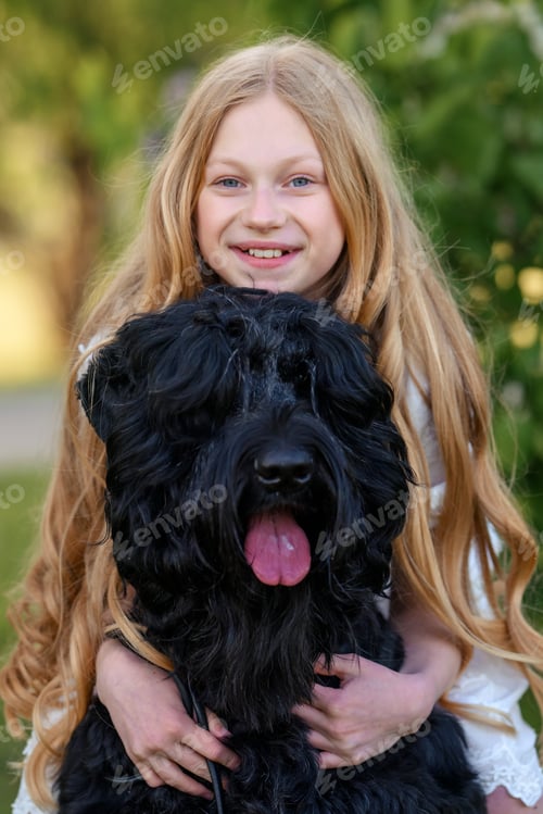 Preview: beautiful girl sitting in the spring park with bouquets of flowers and a black Russian terrier dog