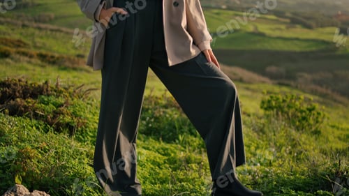 Preview: Stylish woman standing grass in front beautiful cloudy sky. Serious girl posing.