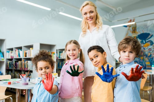 Preview: selective focus of cheerful woman standing with multicultural kids showing colorful hands with