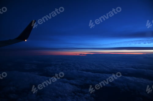 Preview: Beautiful shot of an airplane flying above white clouds at sunset