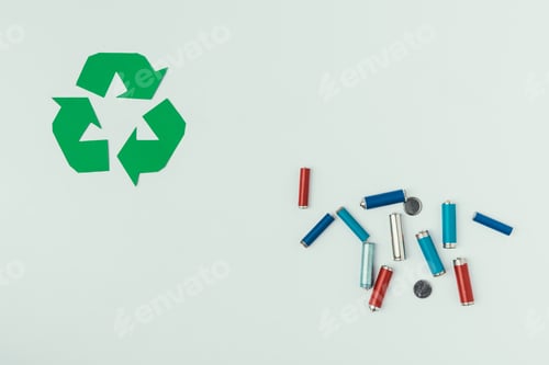 Preview: top view of recycle sign and various types of batteries isolated on grey
