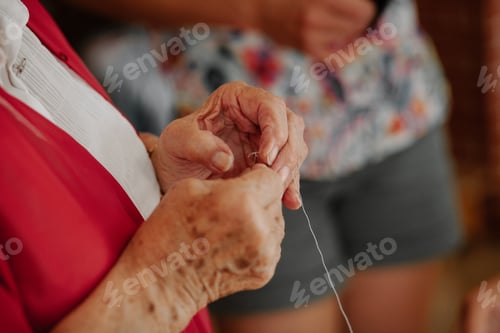 Preview: Old woman putting a thread through a sewing needle