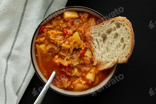 Preview: Homemade Shredded Cabbage and Potato Soup in a Bowl on a black background, top view.