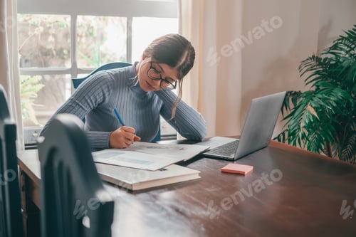 Preview: One young pretty woman studying and doing homework at home on the table.
