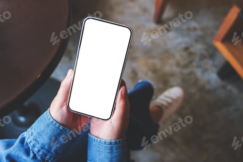 Preview: Top view mockup image of a woman using and holding mobile phone with blank screen