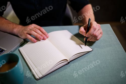 Preview: A man makes a record with a pen in a notebook. A book for recording important matters