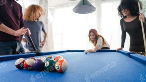 Preview: Male and female friends playing pool together in game room at home