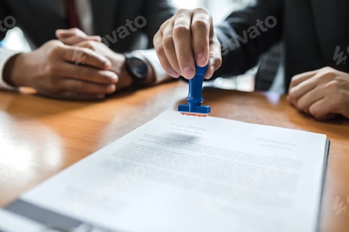 Preview: Businessman stamping with approved stamp on document at meeting.