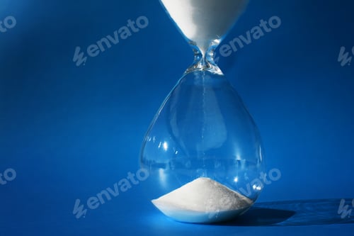 Preview: Hourglass timer or clock with white sand against a blue background. simple, minimal time concept