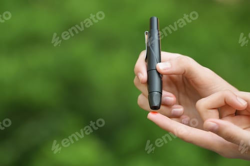 Preview: Woman using lancet pen on blurred background. Diabetes control