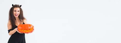 Preview: Banner smiling brunette woman in halloween makeup posing with carved pumpkin copy space