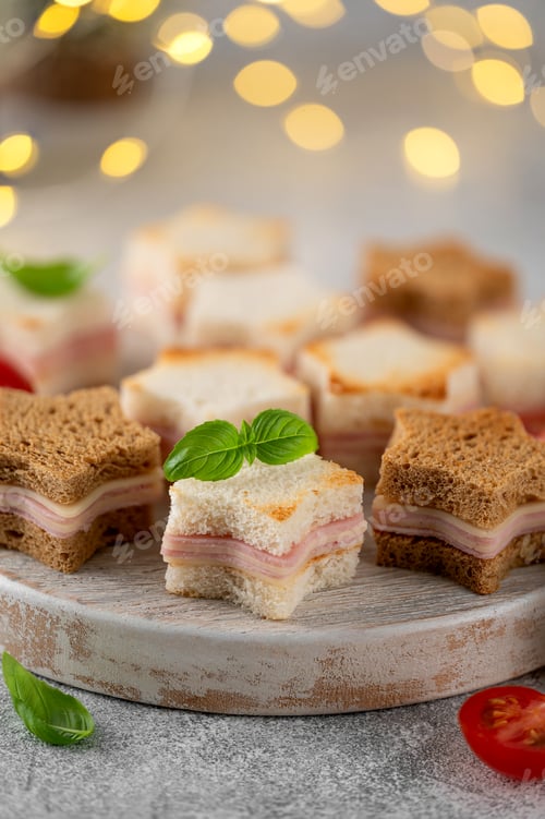 Preview: Christmas star shaped cheese and ham mini sandwiches on a wooden board. Festive food
