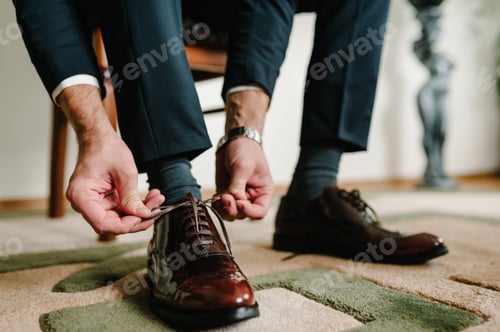 Preview: The groom morning before wedding ceremony wears shoes. Businessman tie the laces on the shoes. Men's