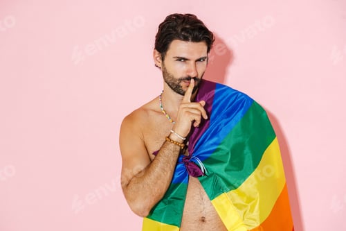 Preview: Young shirtless man with rainbow flag showing silence gesture